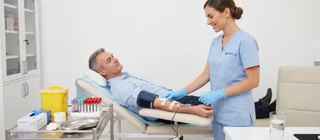 Nurse monitoring a therapeutic phlebotomy for a semi-reclined patient at Medical Time hospital in Belgrade